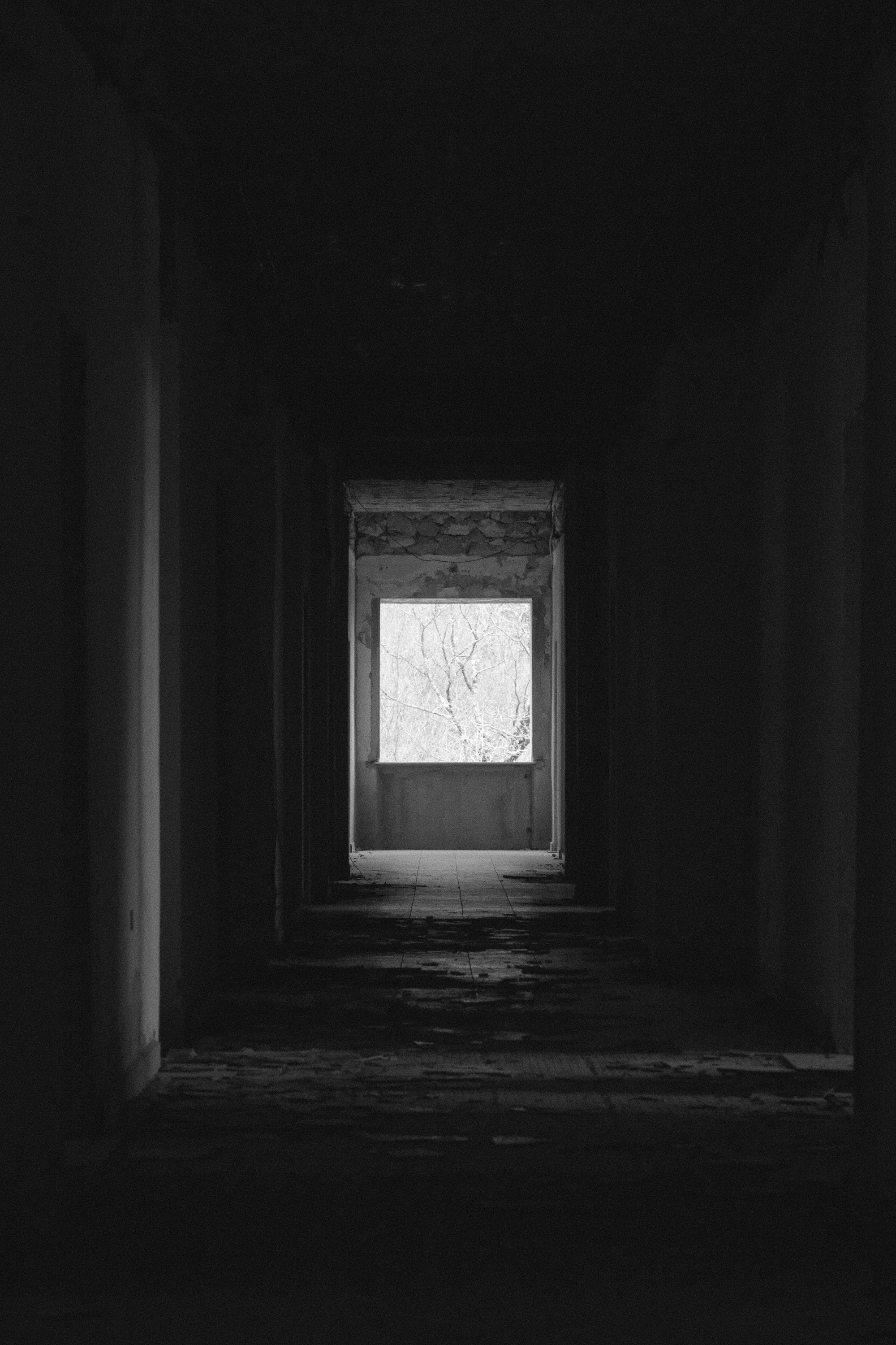 A long, quiet hallway in an empty house, light at the far end.
